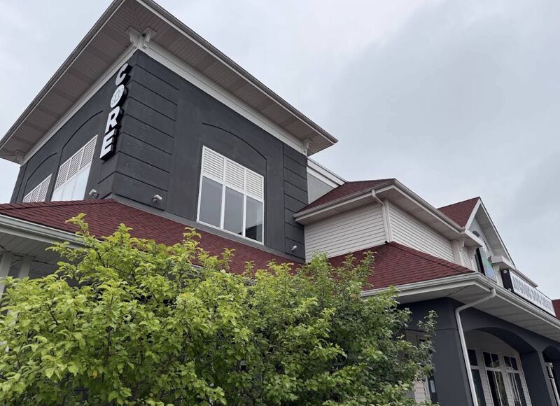 Commercial building exterior with dark siding, a shingle roofline and gutters