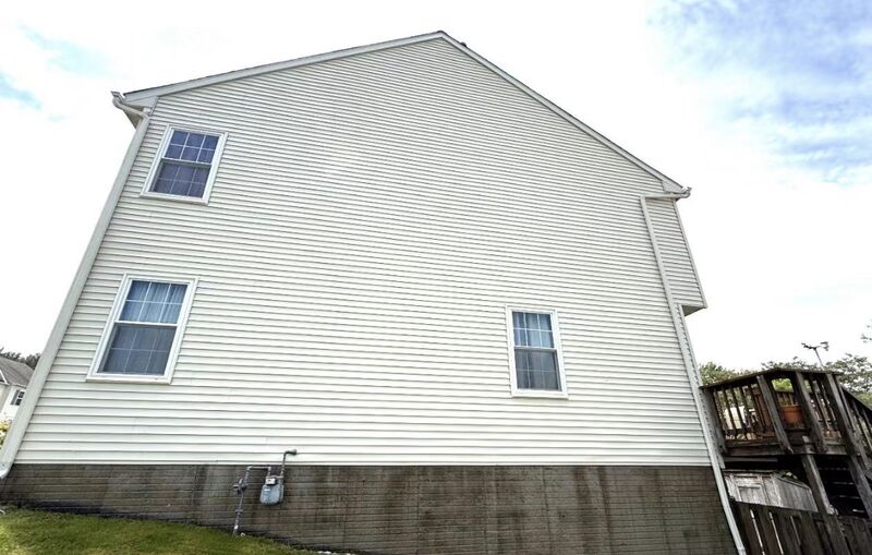 The same house gable after soft washing, with the cream vinyl siding an even, clean color